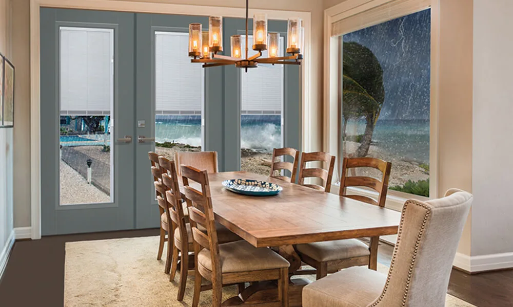 Gray patio doors with blinds between the glass beside a dining table