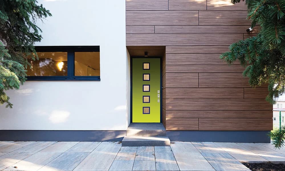 A green modern entry door with a column of small lites beside wood siding