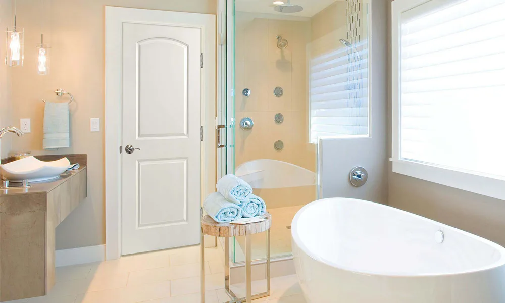 A white arched two-panel molded interior door in a bathroom