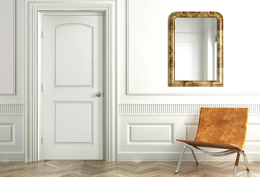 A white arched two-panel molded door in a paneled room