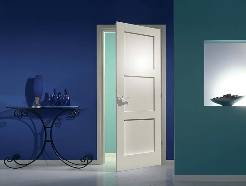 A white stile and rail panel door standing open in a blue room